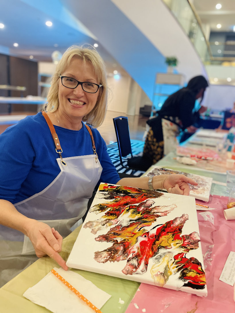 A VIP guest proudly showing her finished fluid art canvas